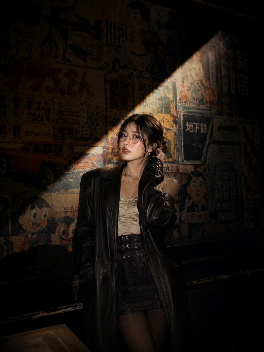 Photograph: Cinematic nighttime portrait of a stylish young Asian woman standing on an esc...